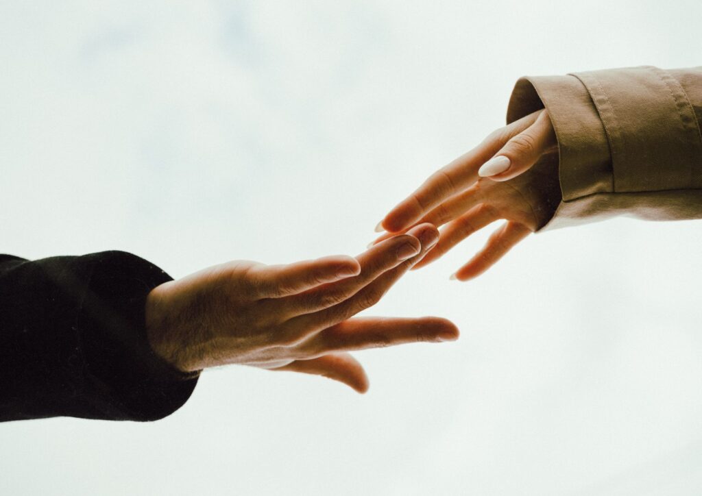 A tender moment captured as two hands reach out towards each other with a soft background.