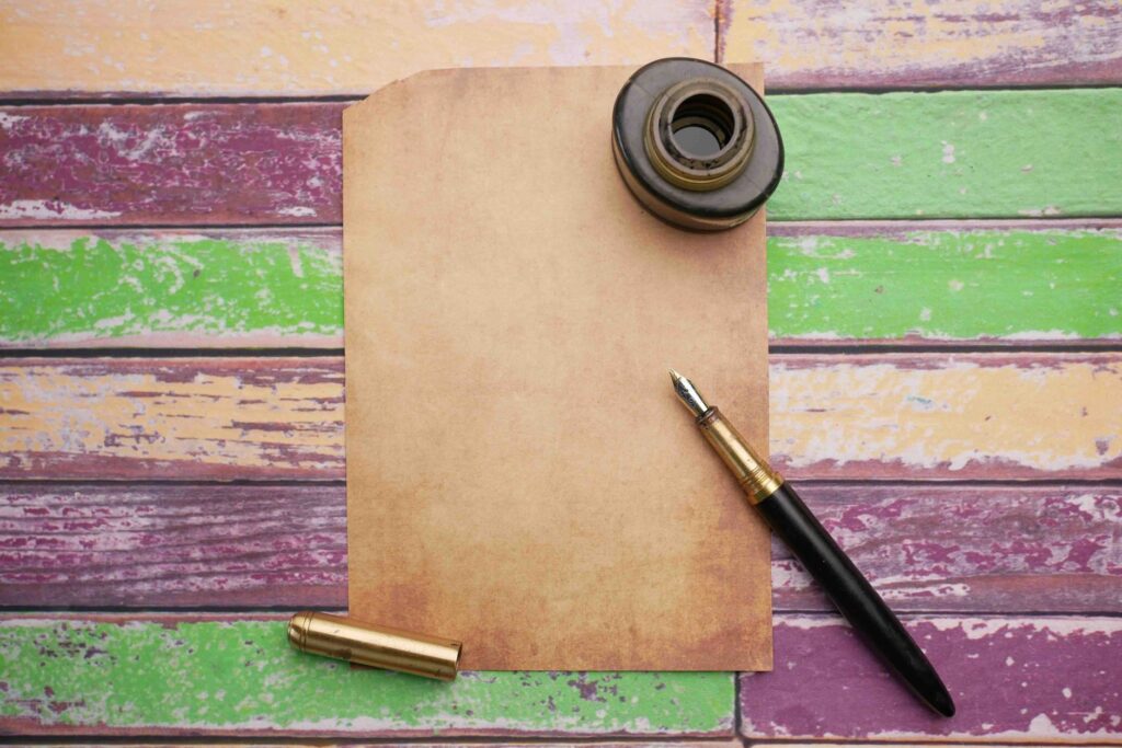 Flat lay of vintage paper with ink bottle and pen on a colorful wooden surface, an image for Muhammad in the Bible: Is He Foretold by Moses and Jesus