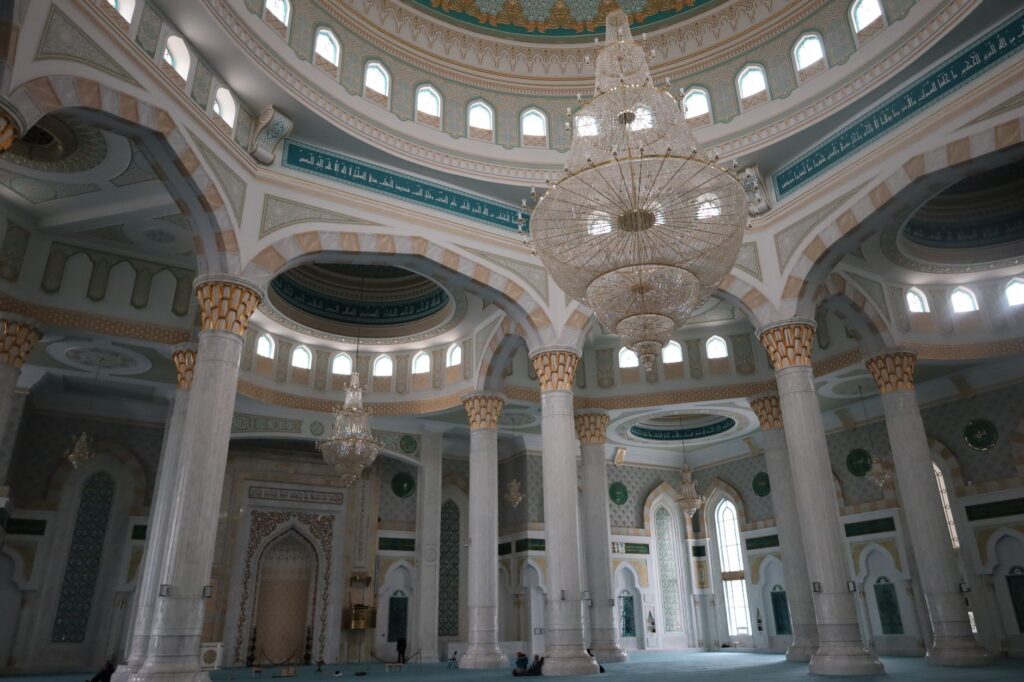 Beautiful mosque interior featuring intricate chandeliers and decorated columns.