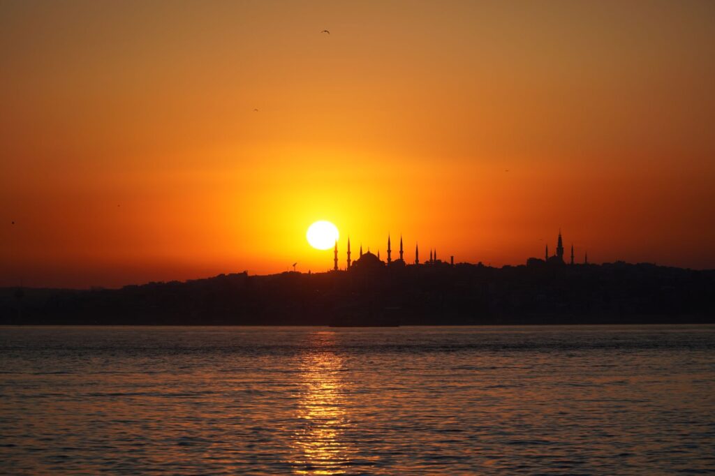 Serene sunset over Istanbul skyline, casting reflections on the water. Perfect for travel and nature themes.