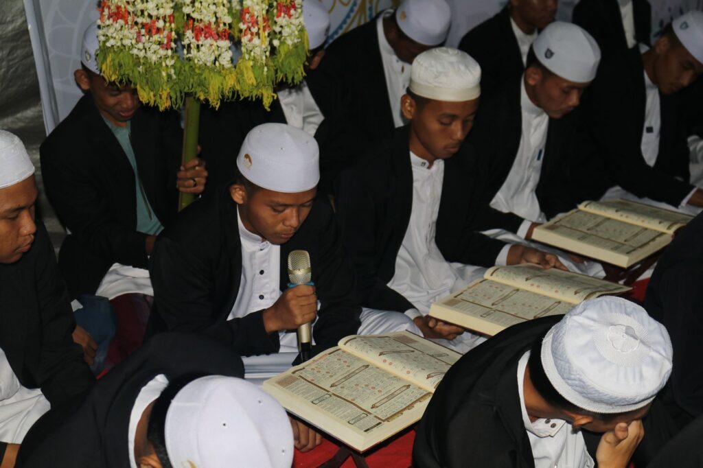 Men in traditional attire reading religious texts during a prayer gathering indoors, an image for Variant Readings of the Quran: Do They Disprove Preservation