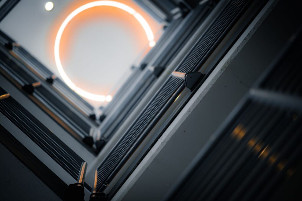 Artistic view of a modern elevator shaft featuring a circular light and sleek metal lines.