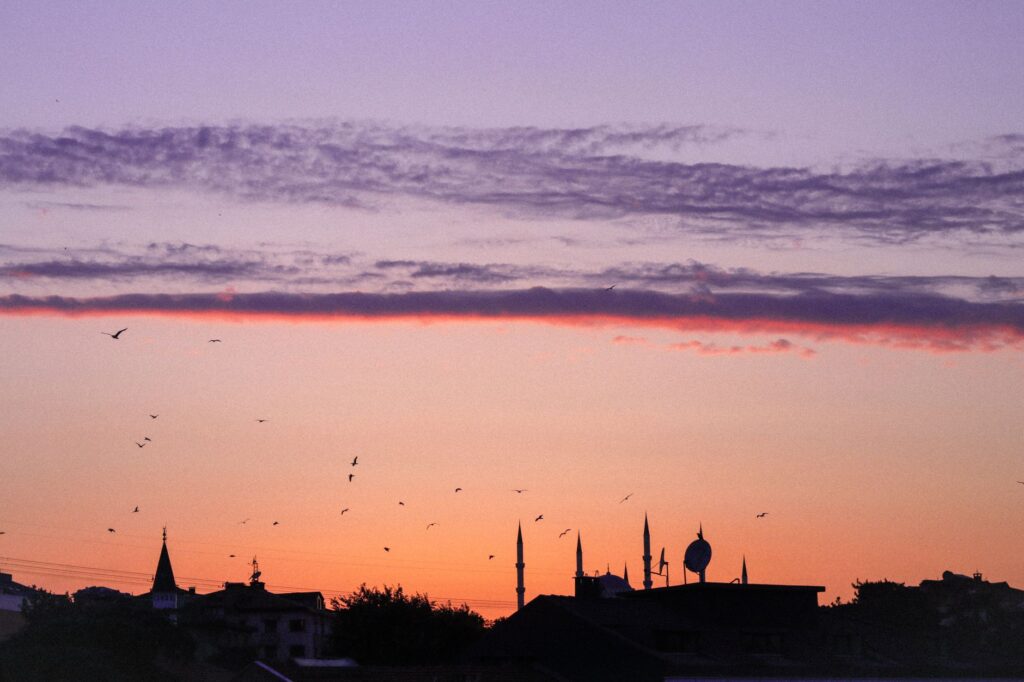 Silhouette of city skyline with minarets against a colorful sunrise sky, an image for Is Islam a Religion of Peace? What the Terrorism Data Shows