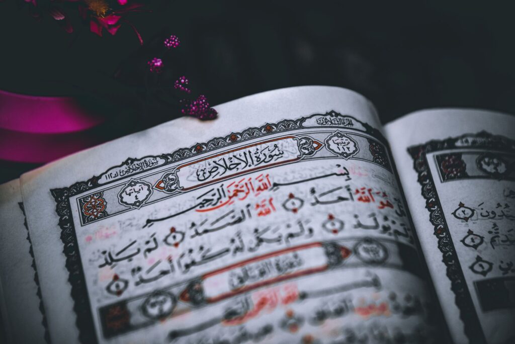 Close-up of an open Quran showing intricate Arabic script and ornate design elements.