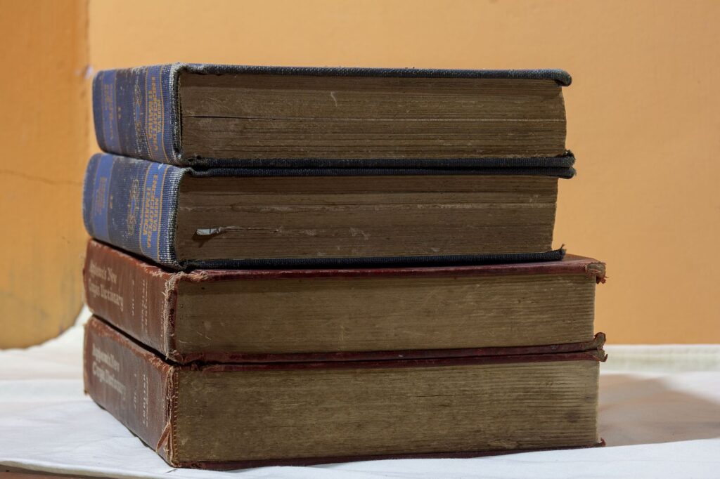 A stack of vintage books on a wooden table, capturing classic literary charm, an image for Inconsistent Revelations: Why Do Prophets' Messages Differ