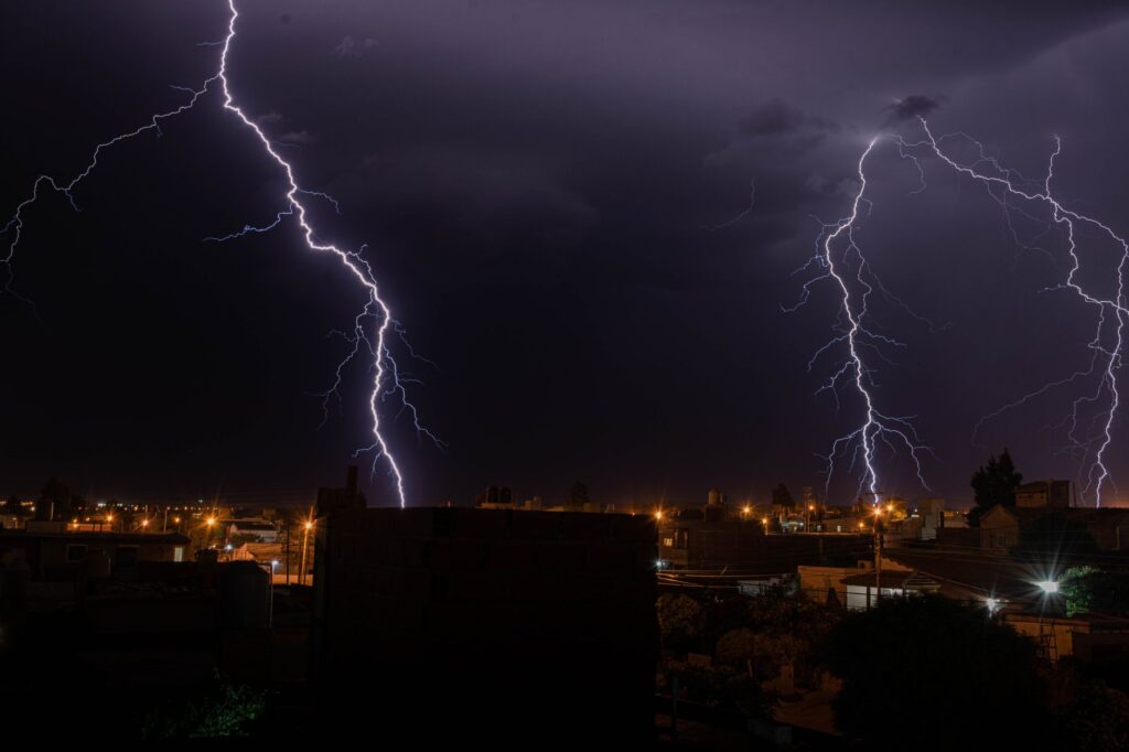 Intense lightning illuminates a city during a nighttime thunderstorm, showcasing nature's power, an image for God of Gaps: Is God Just an Explanation for What We Do Not Know