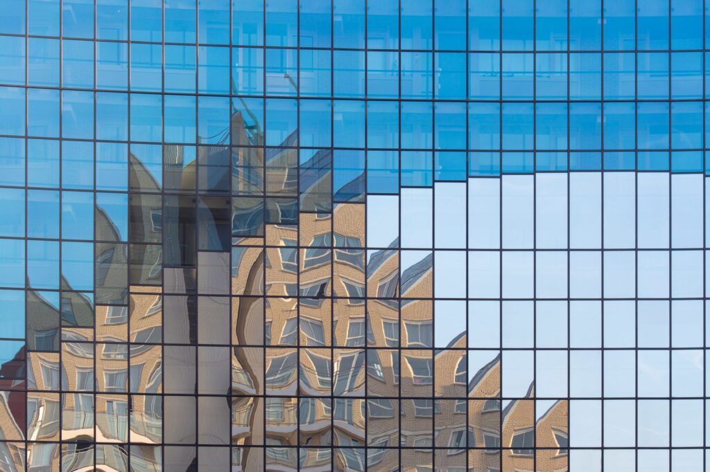 A glass facade reflecting a distorted view of urban buildings in Voorburg, Netherlands.