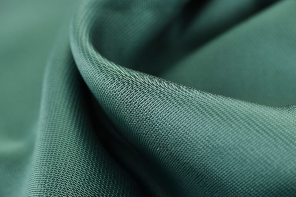 Close-up texture shot of elegant green satin fabric highlighting its smooth and soft surface, an image for Hijab, Male Control or Divine Command