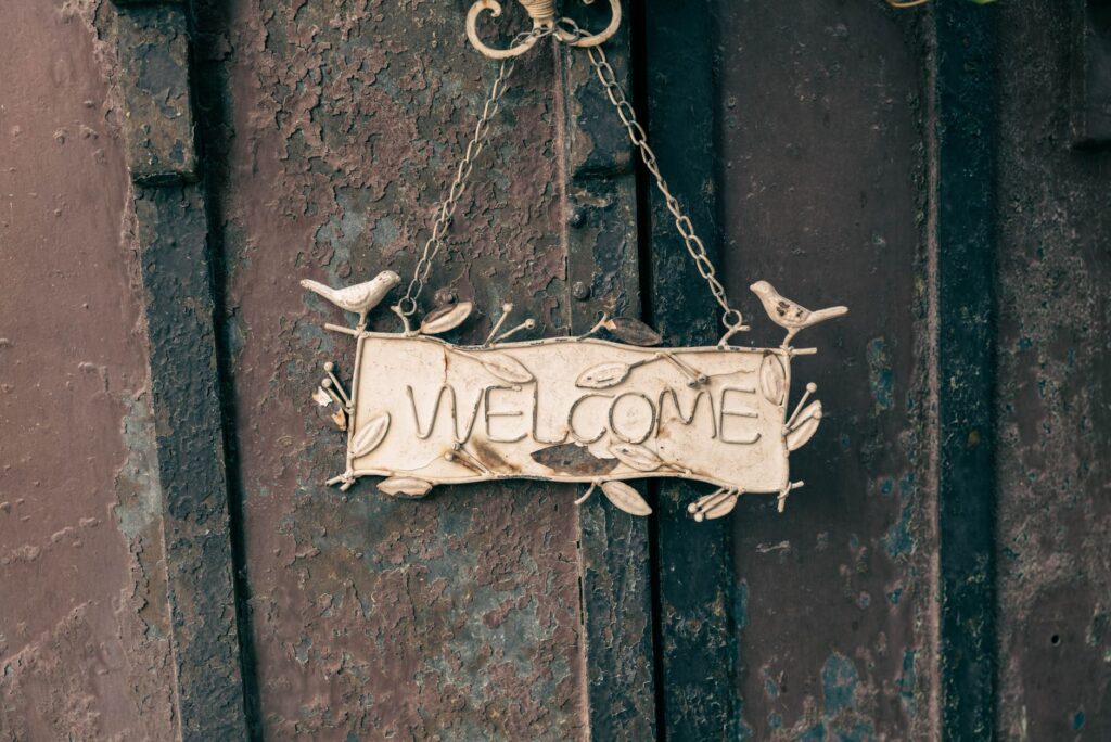 A rustic metal welcome sign with bird decorations, perfect for home decor or entryways.