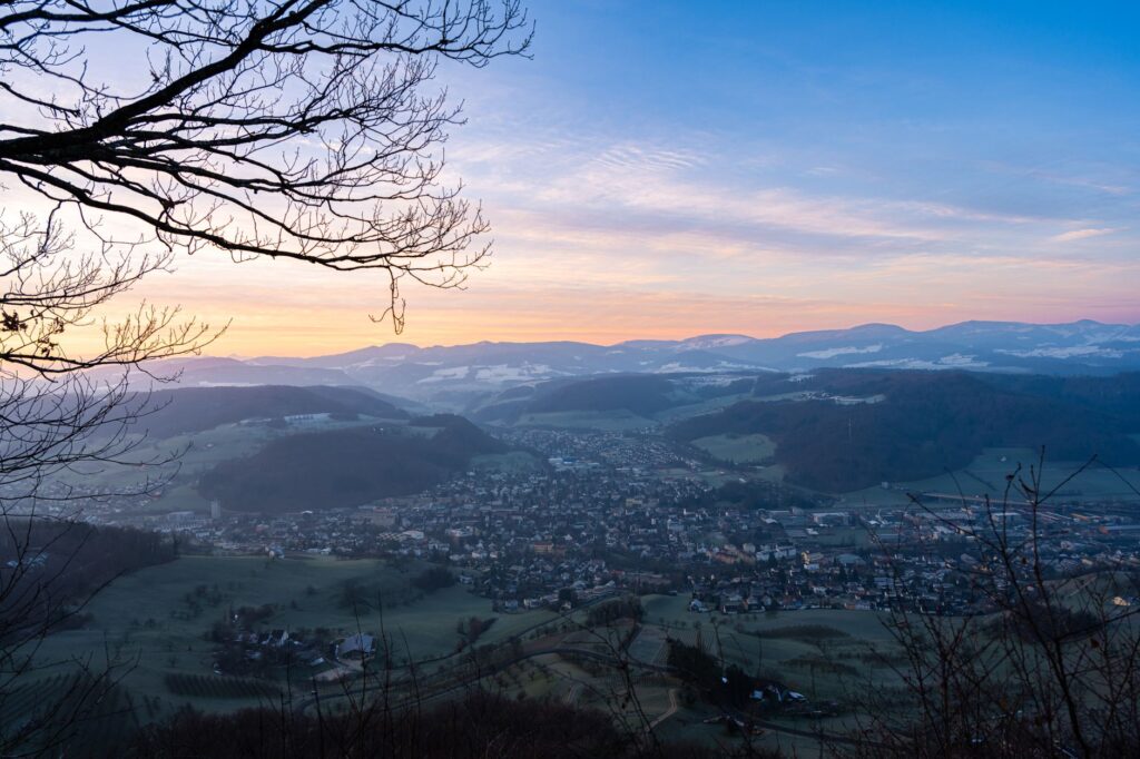 A breathtaking aerial view of a town surrounded by mountains at sunrise, capturing the serene landscape and vibrant sky.
