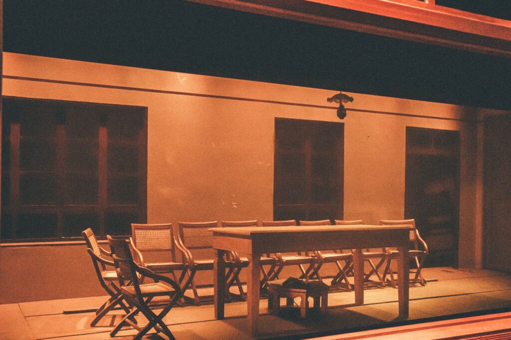 An empty minimalist dining area with warm lighting and wooden furniture, captured at night.