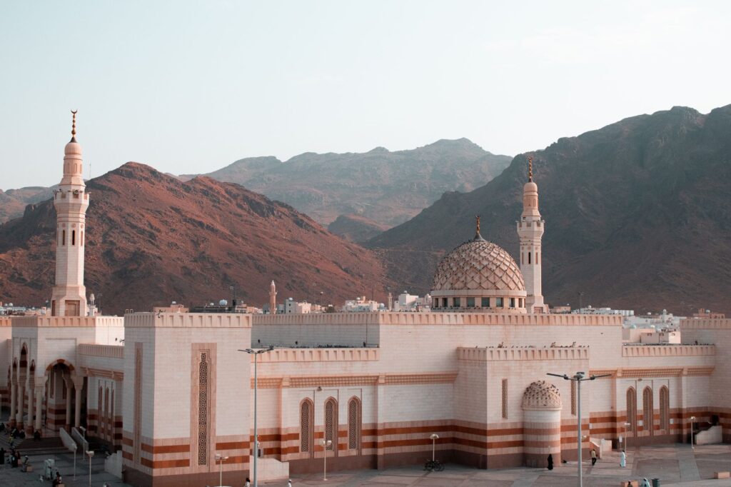 Beautiful mosque with minarets stands against rugged mountain landscape, Saudi Arabia, an image for Abrogation: The Quran's Two Voices in Mecca and Medina