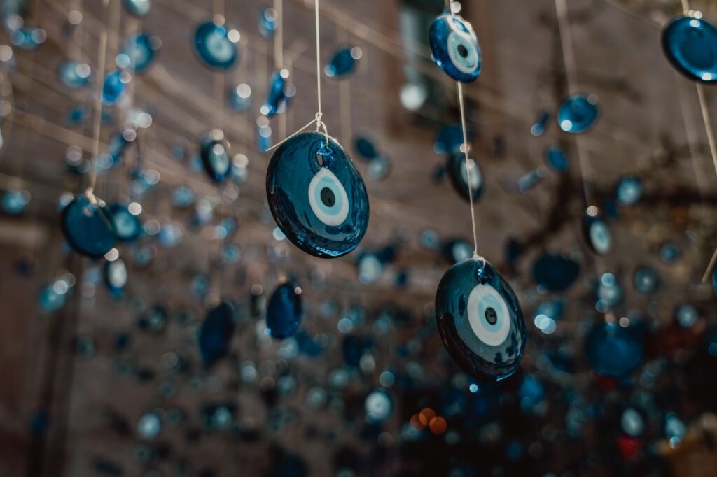 Close-up of numerous blue evil eye charms hanging on strings, capturing tradition and decoration.