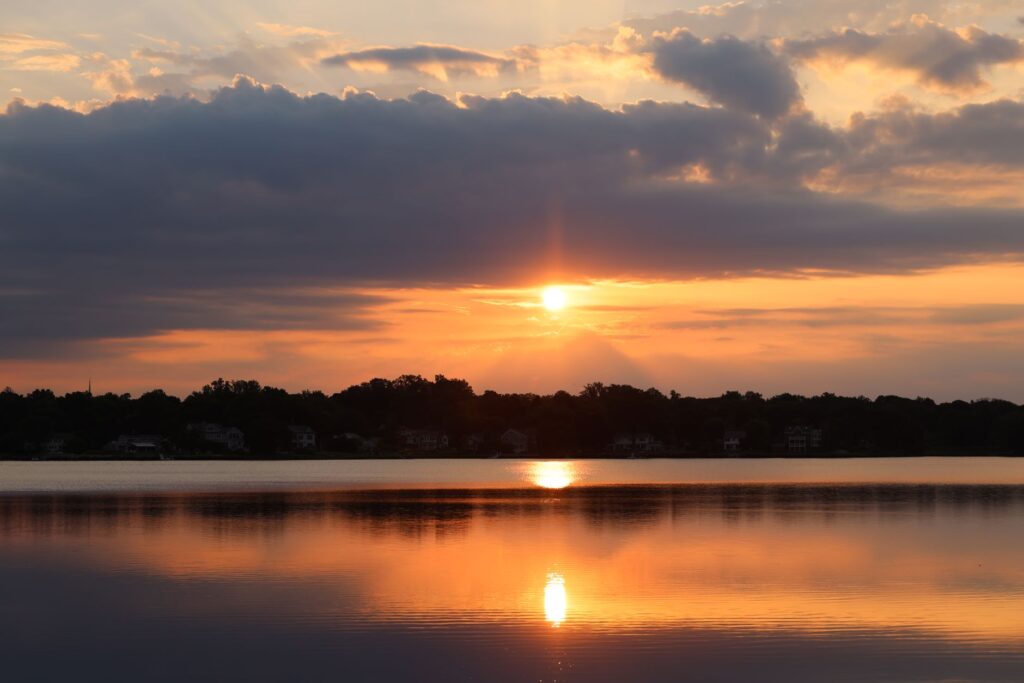 A breathtaking sunset reflecting over a tranquil lake, highlighting the serene beauty of nature, an image for Dhul-Qarnayn and the Sun Setting in a Muddy Spring