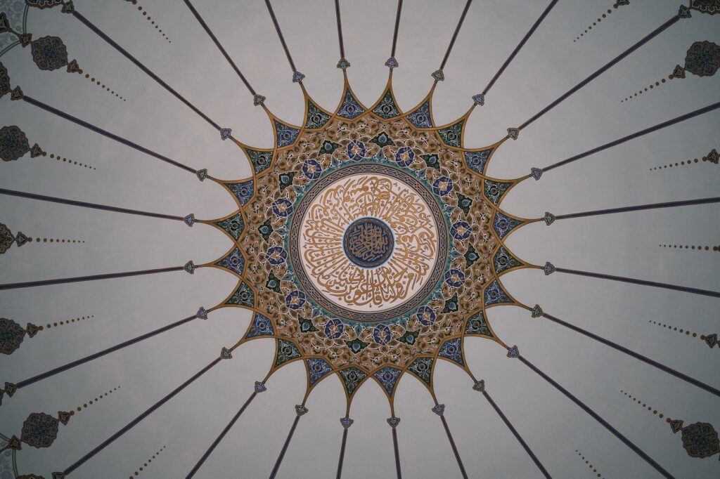 Detailed view of an ornate mosque dome ceiling featuring Islamic geometric and calligraphic designs.