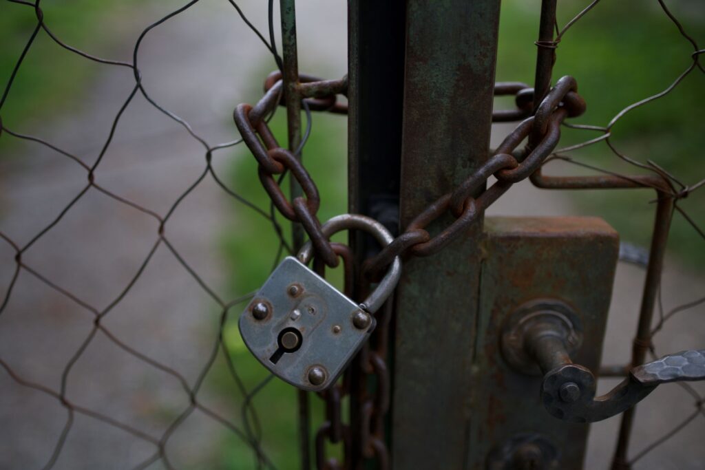 A close-up of a rusty padlock and chain securing a metal fence gate, outdoors, an image for When Religion Was Imposed, Not Discovered