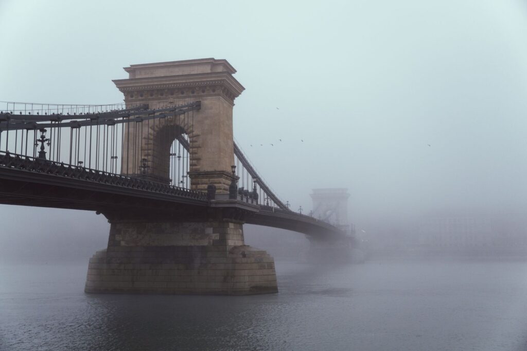 The iconic Chain Bridge of Budapest enveloped in an ethereal fog over the Danube River.