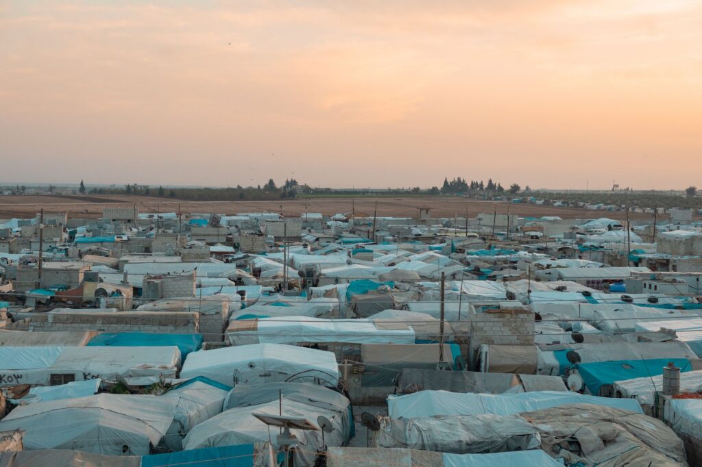 Aerial photo of a sprawling refugee camp under a vibrant sunset sky, an image for Suffering and God: The Islamic Account