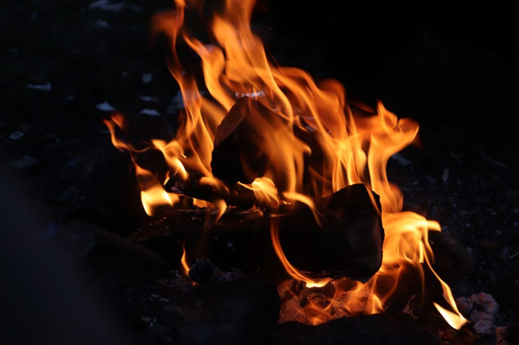 Vivid campfire flames creating warmth and light in a dark outdoor setting.