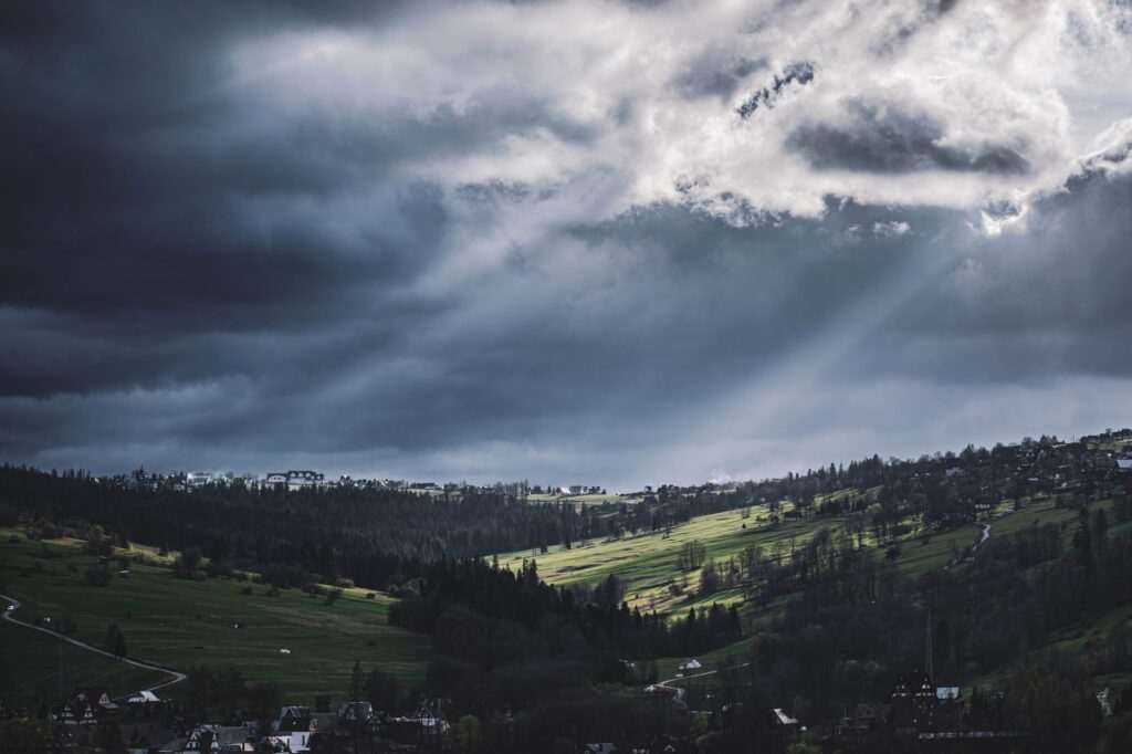 Moody landscape of Biały Dunajec, Poland, with dramatic clouds and sunlight breaking through, an image for Universal Salvation: Why Does God Not Simply Forgive Everyone