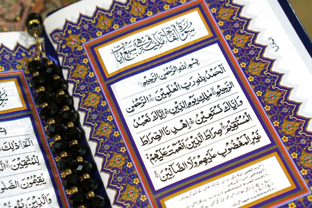 Close-up of an ornate Quran page with prayer beads, showcasing Islamic calligraphy and design, an image for If the Quran Calls Jesus the Word of God, Is He Divine