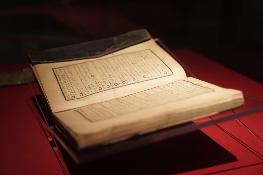 Open ancient manuscript on red background displayed in Bakı, Azerbaijan.