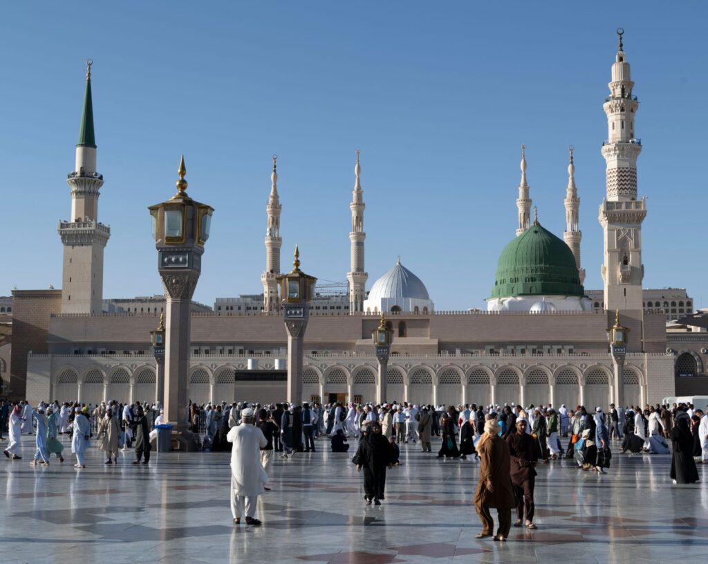 Pilgrims gather at the courtyard of Al-Masjid an-Nabawi, showcasing Islamic architecture in Medina, Saudi Arabia.