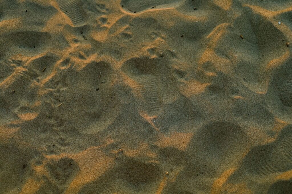 Footprints in textured golden beach sand with a warm sunset glow, an image for Identity After Islam: Can You Leave and Still Be Yourself