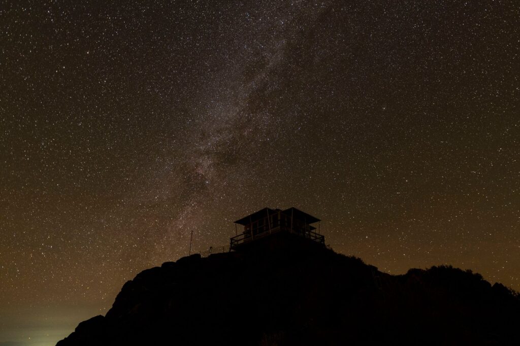 Silhouette of cabin against a starry sky with Milky Way visible. Perfect for astronomy enthusiasts.