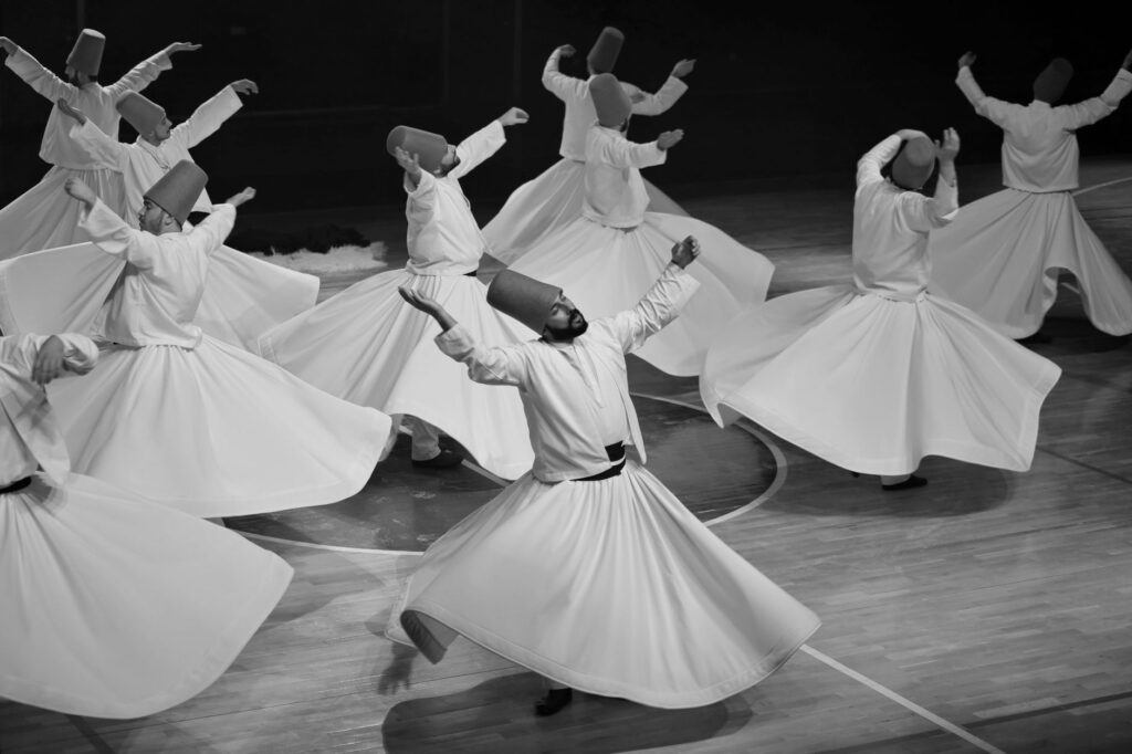 Black and white image of whirling dervishes in traditional Sufi dance, showcasing spiritual expression.