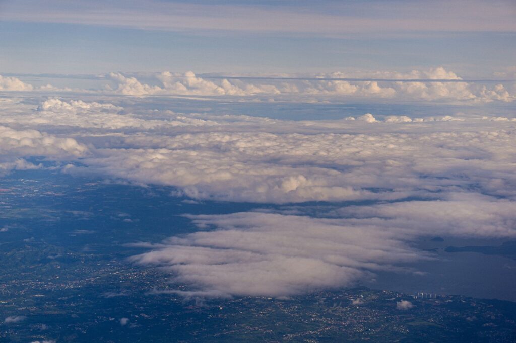 Captivating aerial view of fluffy clouds hovering over a landscape and water body during the day, an image for Flat Earth, Seven Heavens and Shooting Stars: Is Quranic Cosmology Wrong
