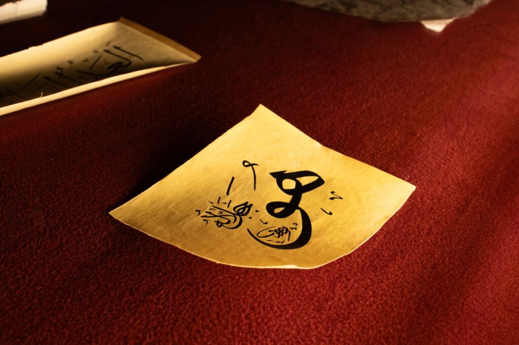 Intricate calligraphy artwork on yellow paper set against a rich red background.