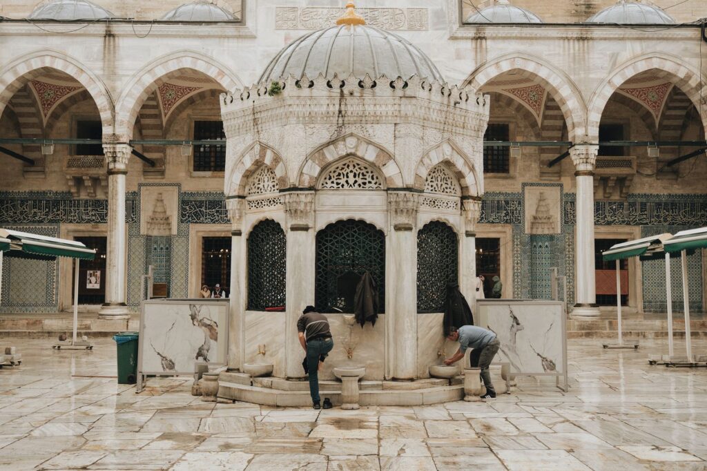 Historic courtyard in Istanbul featuring traditional architecture and a central fountain under cloudy skies.