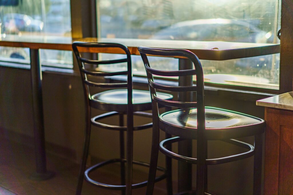 Two empty cafe chairs by a sunlit window, creating a warm and inviting atmosphere, an image for The Social Cost of Leaving: What No One Tells You