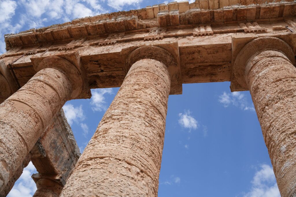 Upward view of ancient stone columns against a clear blue sky at Segesta, Sicily.