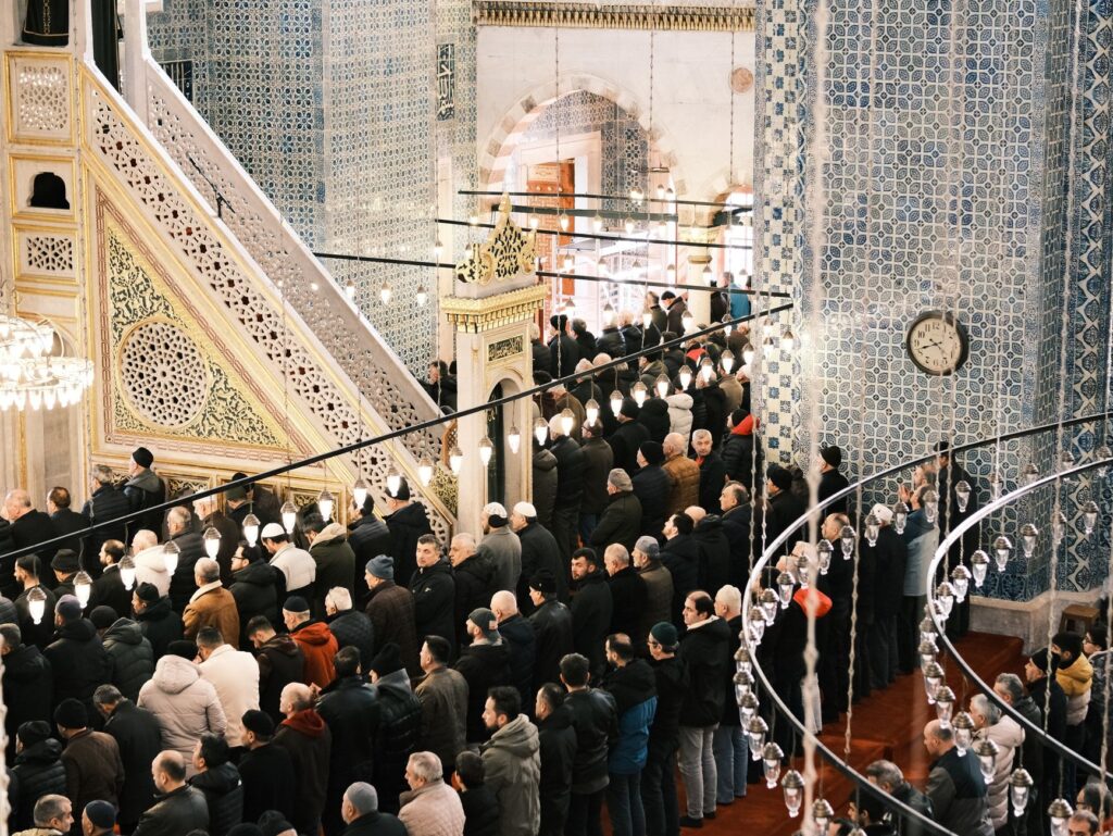 A large congregation of men gathered in a beautifully decorated mosque for prayer, an image for What Draws People to Islam Today