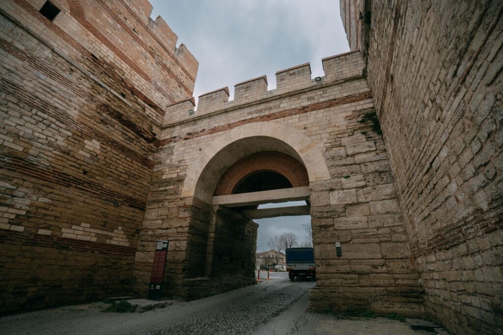 A massive stone gate of an ancient fortress captured from below on a cloudy day.