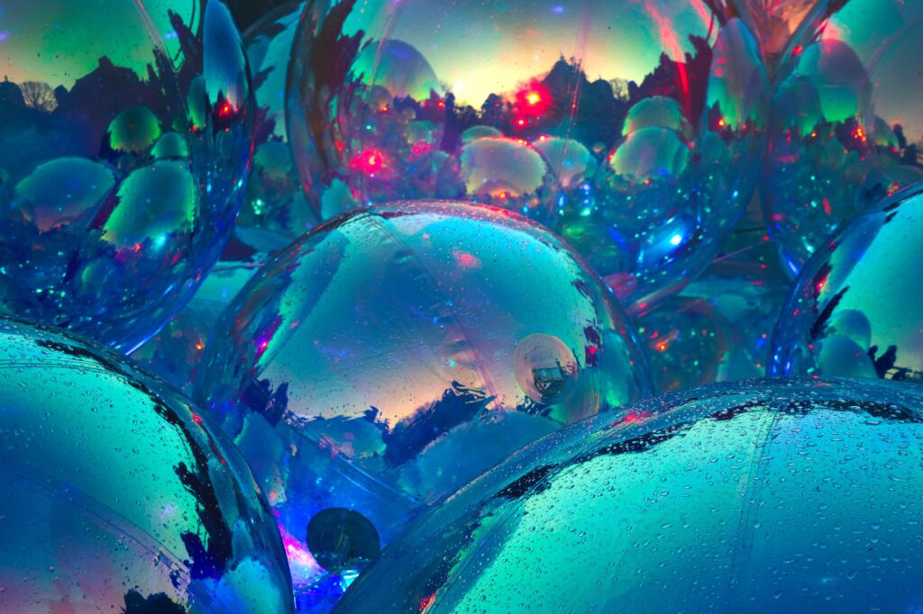 Colorful reflective spheres with water droplets, showcasing a vivid, abstract play of colors in an artistic display.