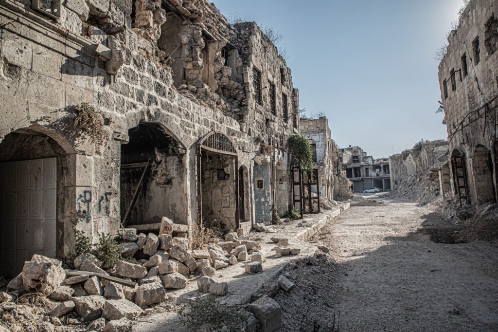 A deserted, war-torn street in Aleppo, captured in daylight, showcasing destruction and desolation, an image for Does Religion Cause Harm? Has It Done Enough Damage