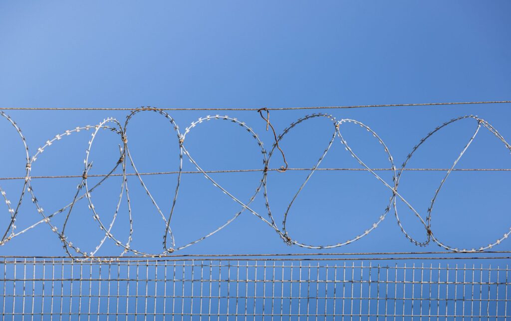 Detailed image of barbed wire fence under clear blue sky, symbolizing security and restriction, an image for Prison Conversion: Why Does Islam Spread So Fast in Prison
