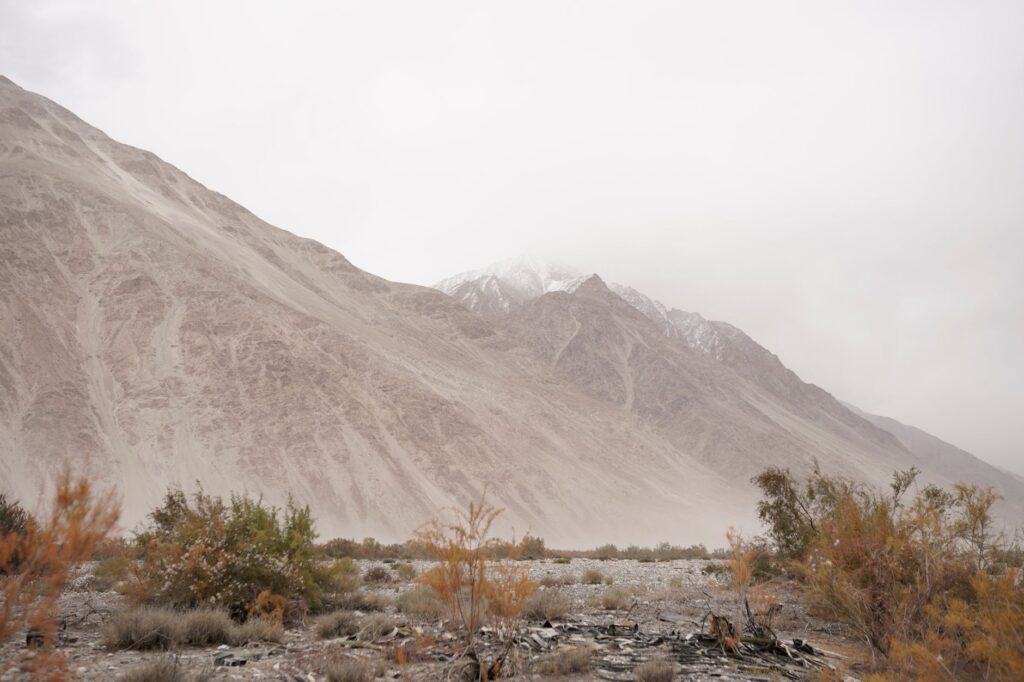 Expansive view of a rugged mountain range enveloped in fog and desert terrain.