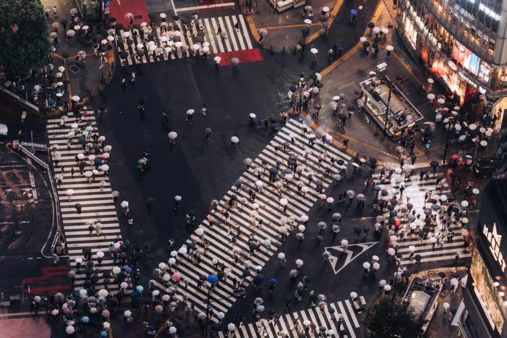 A top-down view of Shibuya Crossing, Tokyo, bustling with people carrying umbrellas on a rainy day, an image for Do Good Non-Muslims Go to Hell? What Happens to Those Who Never Heard