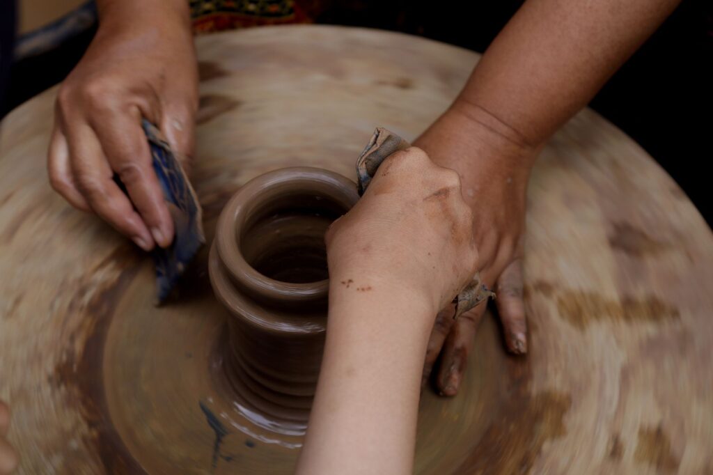 Close-up of hands sculpting clay pottery on a wheel, pottery-making art, an image for Creation Accounts in the Quran: Four Descriptions, One Contradiction