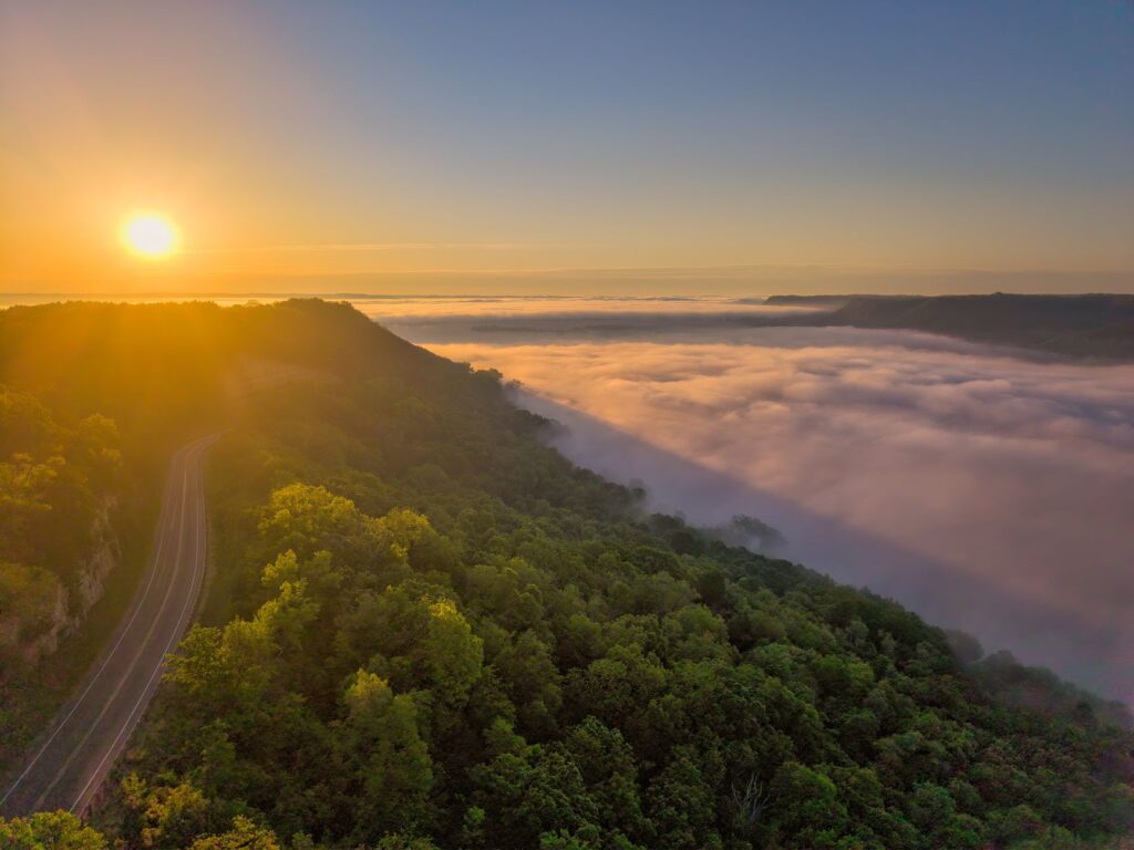 A breathtaking sunrise casts warm light over a fog-covered valley near Weaver, Minnesota, USA.