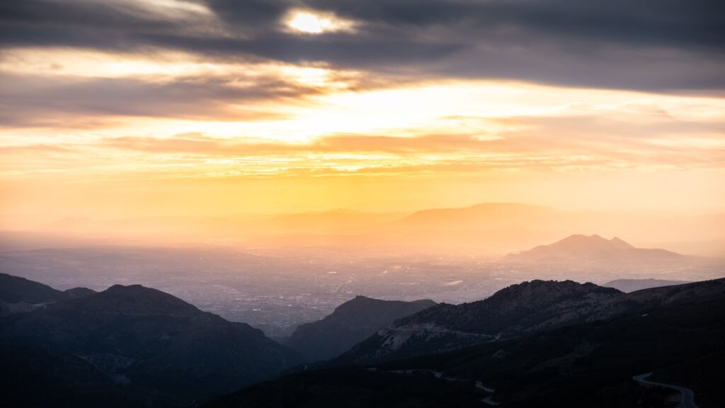 A breathtaking sunrise over a dramatic mountain landscape with a warm glow.