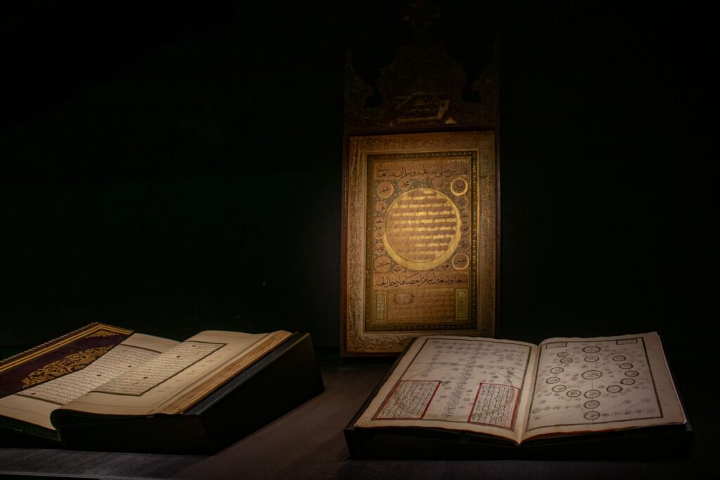 Illuminated ancient manuscripts displayed in a dimly lit Istanbul museum exhibit.