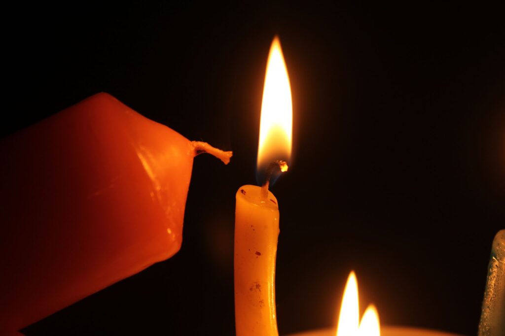 A close-up shot of candles burning in the dark, creating a warm and serene atmosphere.