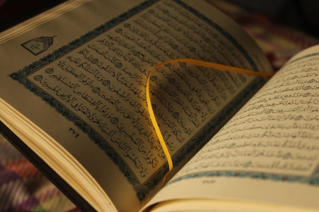 An intimate view of Quran pages highlighted by a yellow ribbon bookmark.