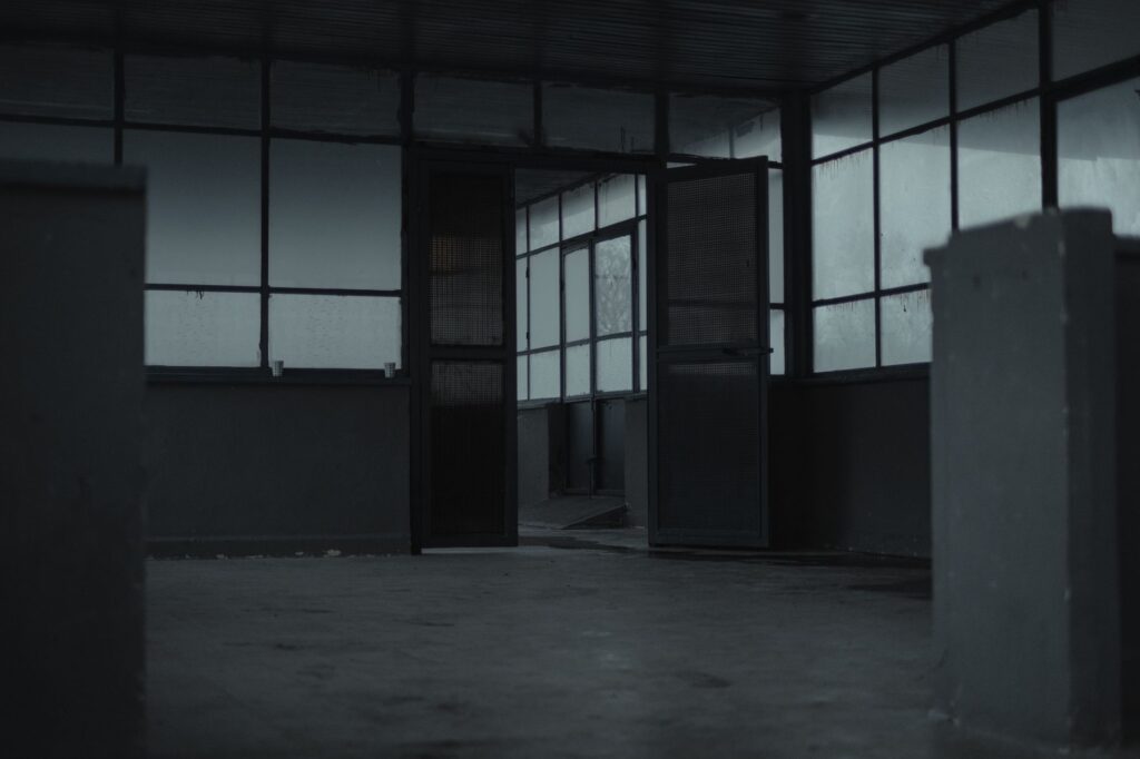 Interior of spacious empty room of gloomy abandoned building with glass windows and opened door