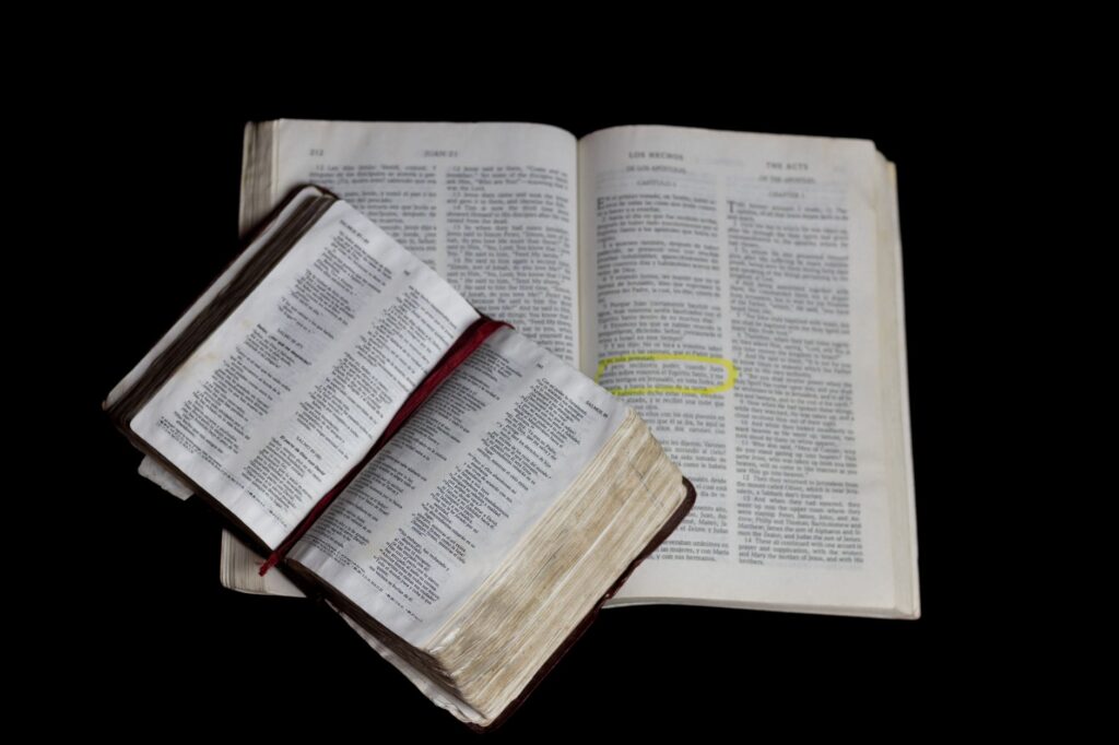 An open Bible on top of another against a plain black background, an image for Bible Stories in the Quran: Recycled or Revealed